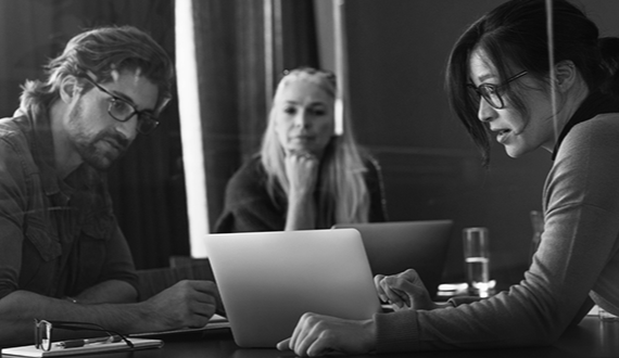 Three team members looking at laptop