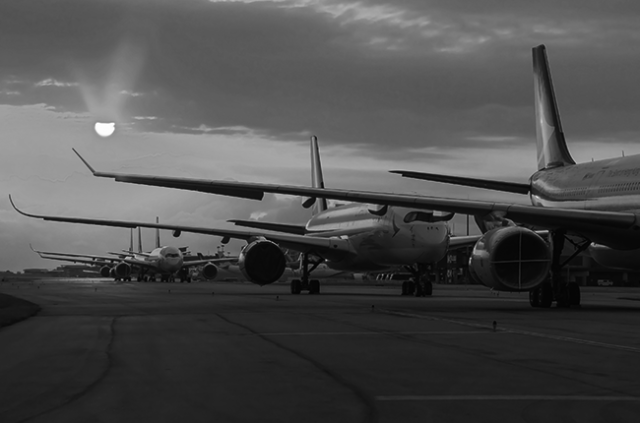 planes sitting on runway with sunset in the background