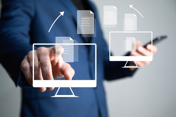 Businessman holds phone in one hand and transfers files with the other.